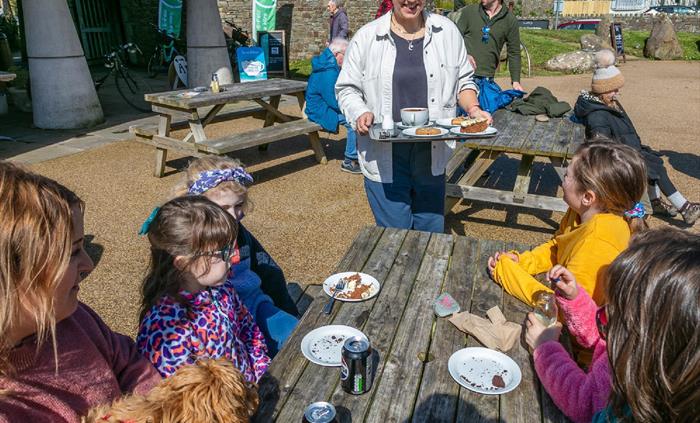 Family enjoying their cakes outside on picnic bench.
